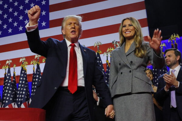 a man and woman standing in front of a flag